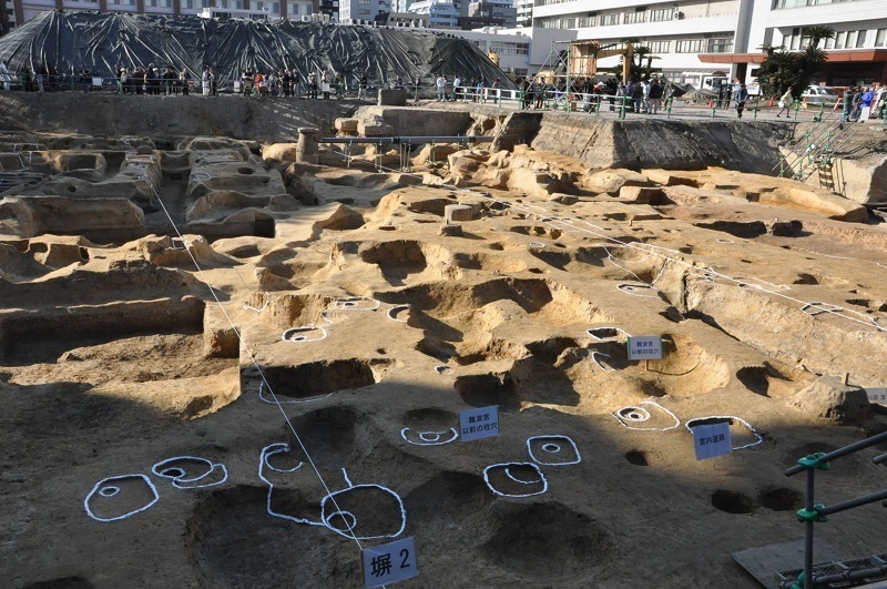 [写真]東から見た後期難波宮跡の発掘現場。東西方向に走る南北のロープが張られた場所に塀があり、塀の間が幅8.8メートルの宮内道路になっていた＝大阪市中央区