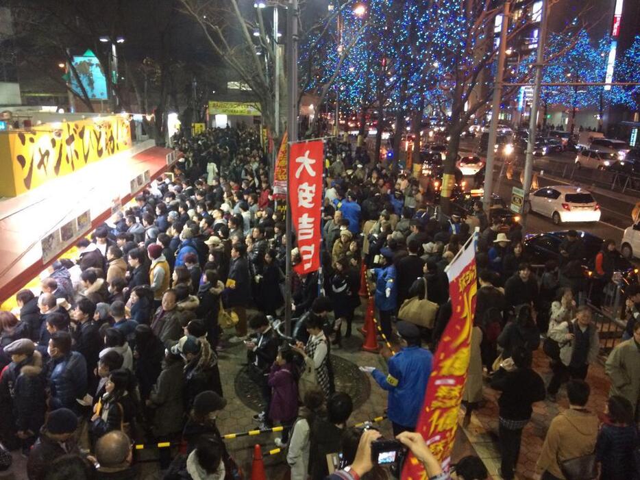 ［写真］年末ジャンボ宝くじを求め、ビルをほぼ囲むような行列ができている＝23日午後6時ごろ、大阪駅前第4ビル付近で