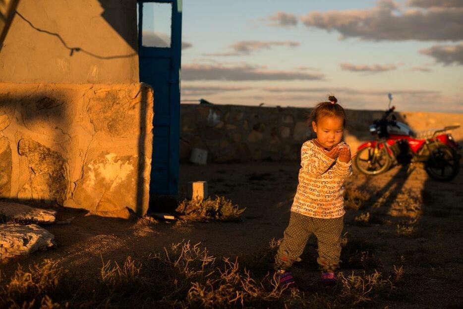 夕日を浴びながら一人ぼっちで遊ぶ子供＝シリンゴル盟・スニド・バロン・ホショー（2016年9月撮影）