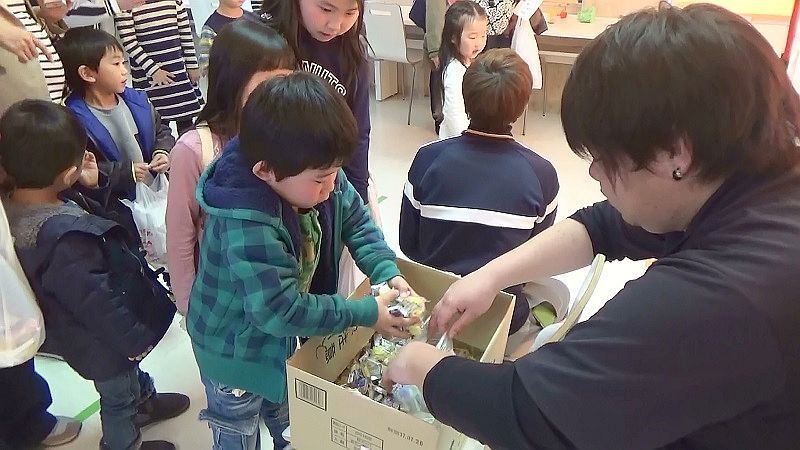 [写真]子どもたちは真剣な表情で駄菓子のつかみ取りに挑戦。「だがしの日は駄菓子と笑顔の交換日」をキーワードに、たくさんの駄菓子が振る舞われた＝大阪市東淀川区の大阪成蹊大学