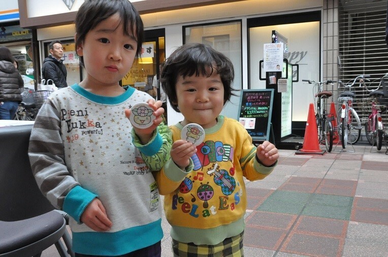[写真]できたばかりの缶バッジを手に喜ぶ子どもたち