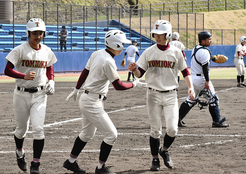 脇町との練習試合で、森野冬麻選手の適時打で生還した富岡西の片山達貴選手（左端）ら＝阿南市桑野町のＪＡアグリあなんスタジアムで、岩本桜撮影