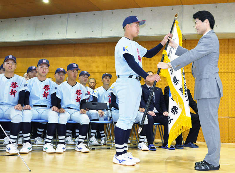 荻原昭人校長から選抜旗を受け取る啓新の穴水芳喜主将＝福井市文京4の同校で、塚本恒撮影