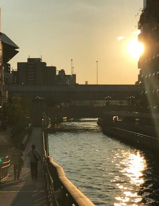 [写真]道頓堀川の水面に夕日が映る。左には湊町リバープレイス=27日午後6時ごろ、大阪市中央区の新戎橋から撮影