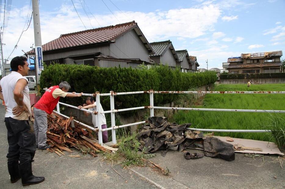 飛び散った瓦や木材の撤去作業をする住民ら（8日、愛知県豊橋市で）