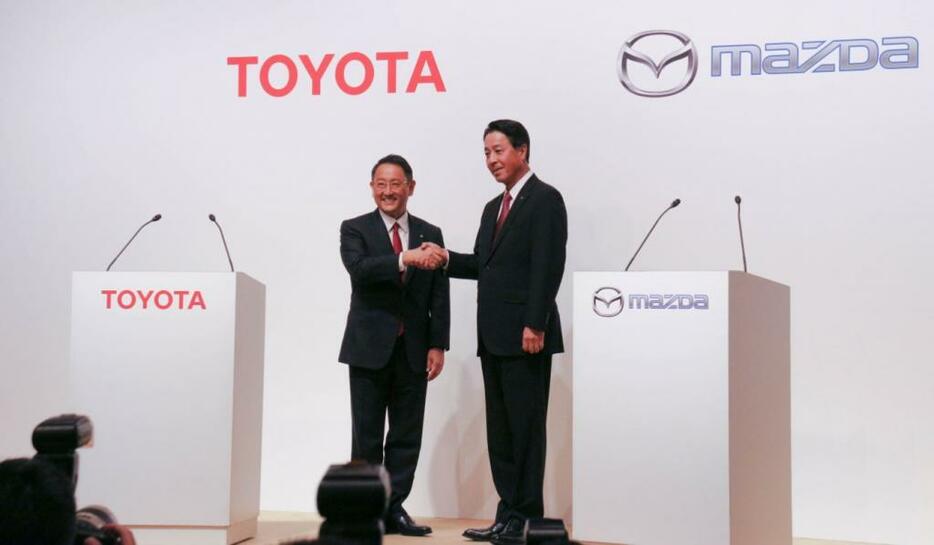 [写真]資本提携を発表した会見で握手するトヨタの豊田章男社長（左）とマツダの小飼雅道社長