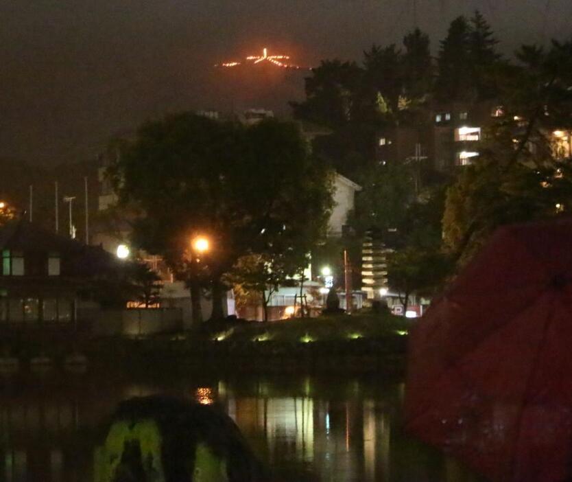 [写真]少し強い雨が降り、傘をさしながら見物する人も。だが、まもなく雲に覆われ見えなくなった=15日午後8時15分ごろ、奈良市内で（撮影：柳曽文隆）