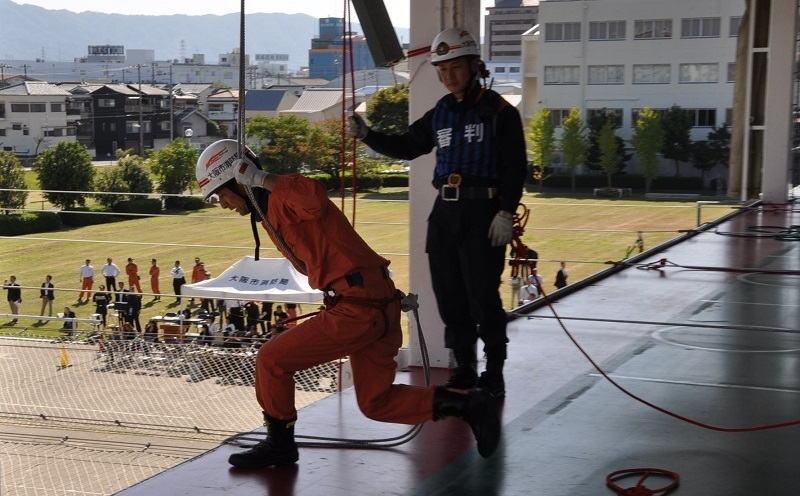 [写真]登はん降下訓練で塔上から地上へ降下する隊員