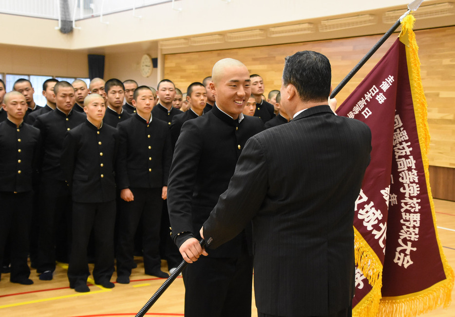 センバツ旗を受け取る鳥取城北・吉田貫汰主将（中央）。右は石浦外喜義校長＝鳥取市の鳥取城北高で、野原寛史撮影