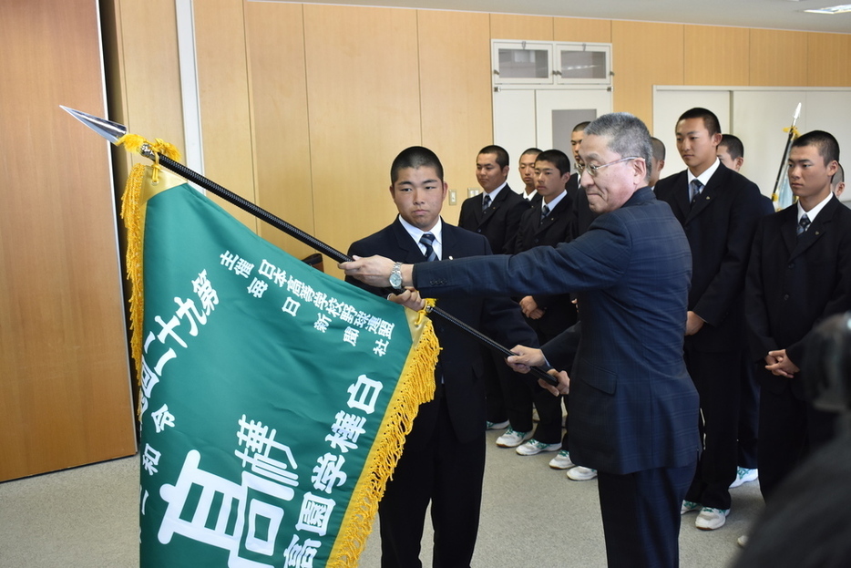 嶋野幸也校長（右）から選抜旗を受け取る白樺学園の業天汰成主将＝北海道芽室町の白樺学園で