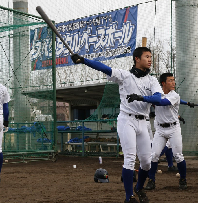 「スペクタクルベースボール」の横断幕の下、打撃練習に励む選手たち＝群馬県高崎市の健大高崎高で