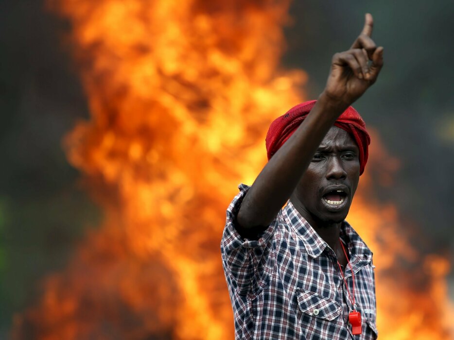 炎を背に叫ぶデモ参加者＝2015年5月21日（写真：ロイター/アフロ）