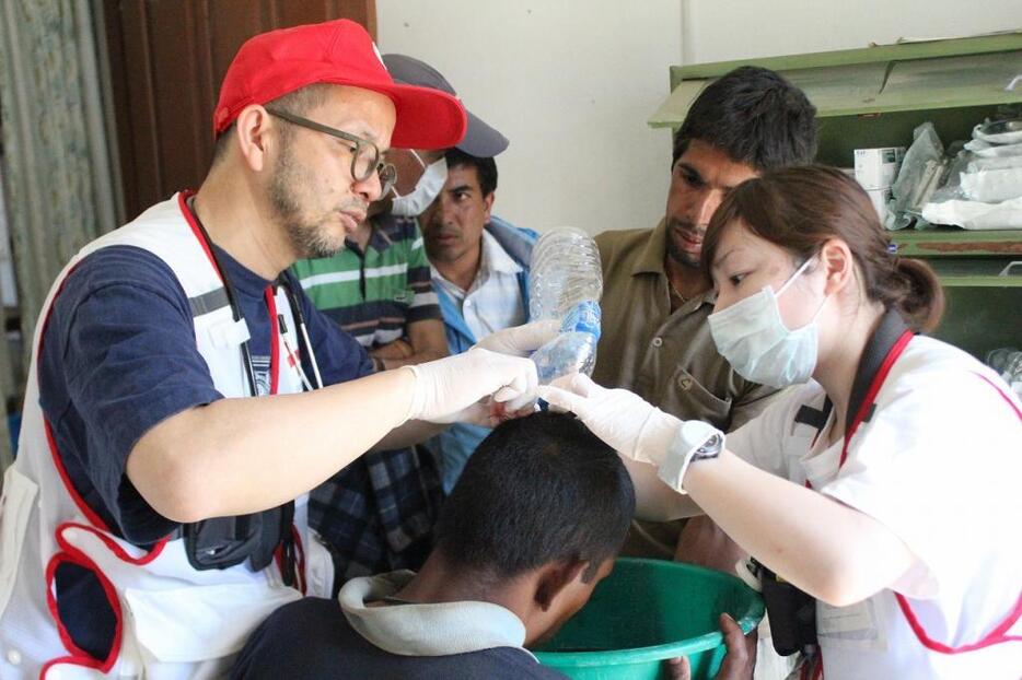 [写真]先遣隊としてネパールを訪れ、メラムチ村の診療所で治療を行う光森健二さん（左）（C）日本赤十字社