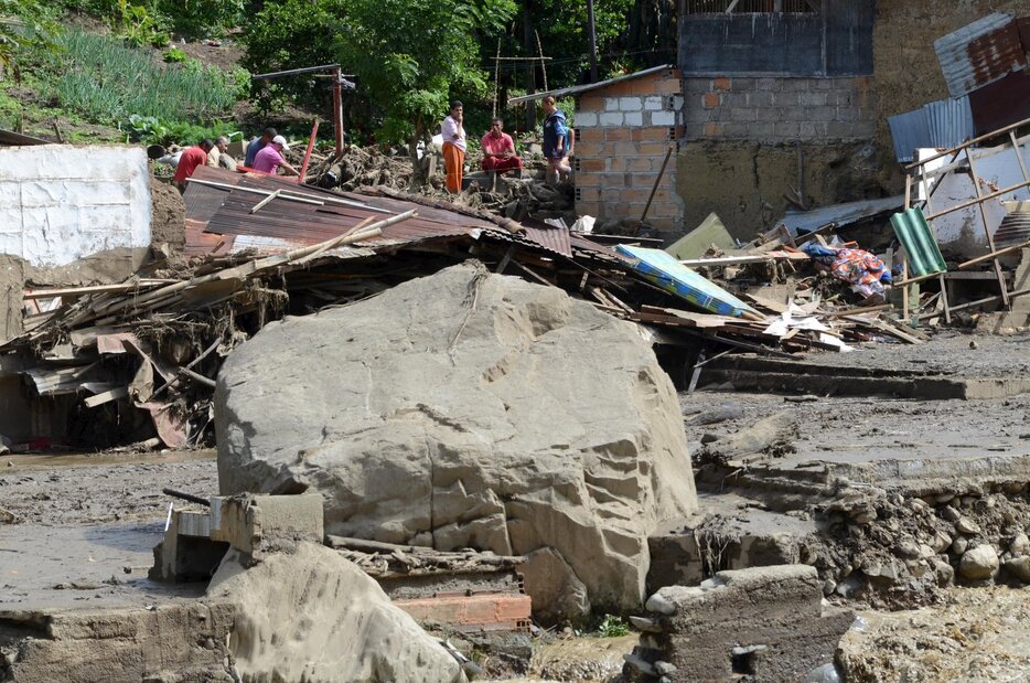 破壊された家のそばにたたずむ住民と土砂で埋まった道＝2015年5月18日（写真：ロイター/アフロ）