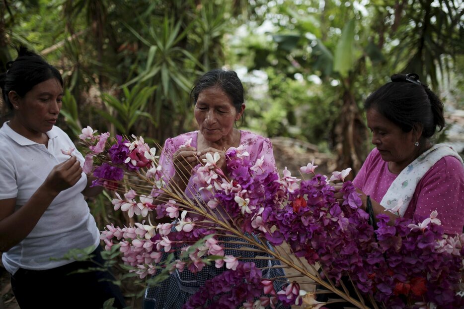 シュロ（ヤシ科植物）の葉に花を飾り付ける女性＝2015年5月11日（写真：ロイター/アフロ）