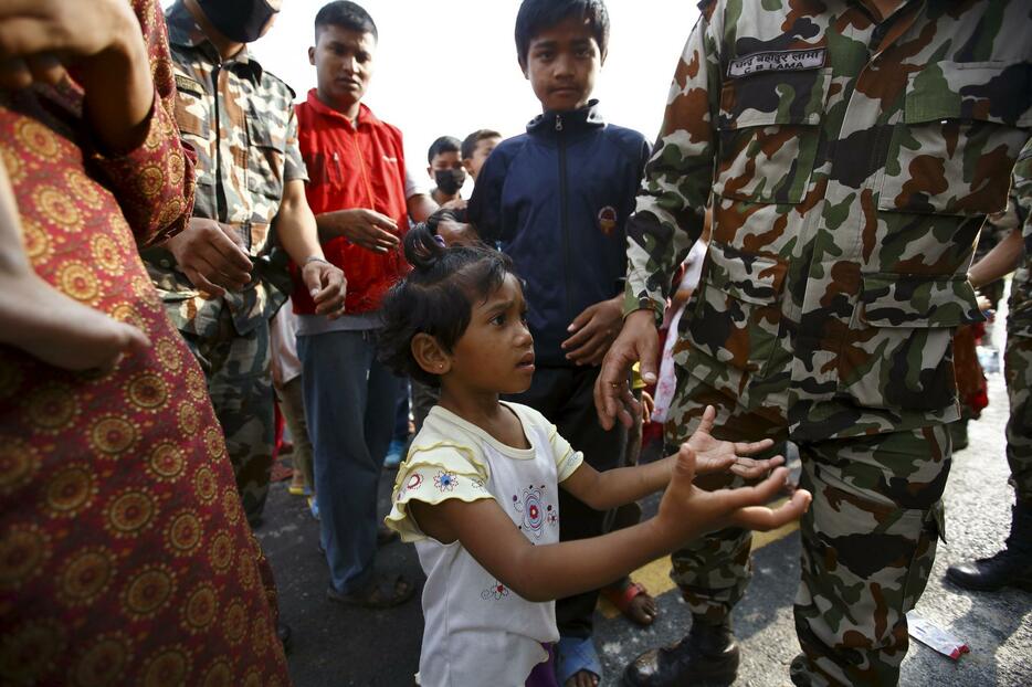 両手を広げ、兵士に食物をもらおうとする少女=2015年5月9日（写真：ロイター/アフロ）