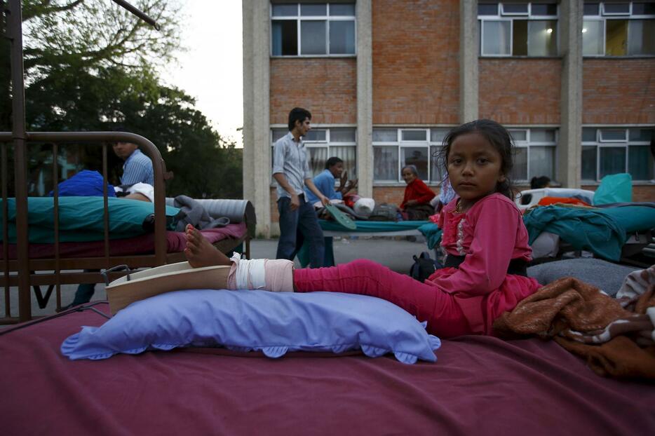 グラウンドのベットに横たわるケガをした少女=2015年5月12日（写真：ロイター/アフロ）