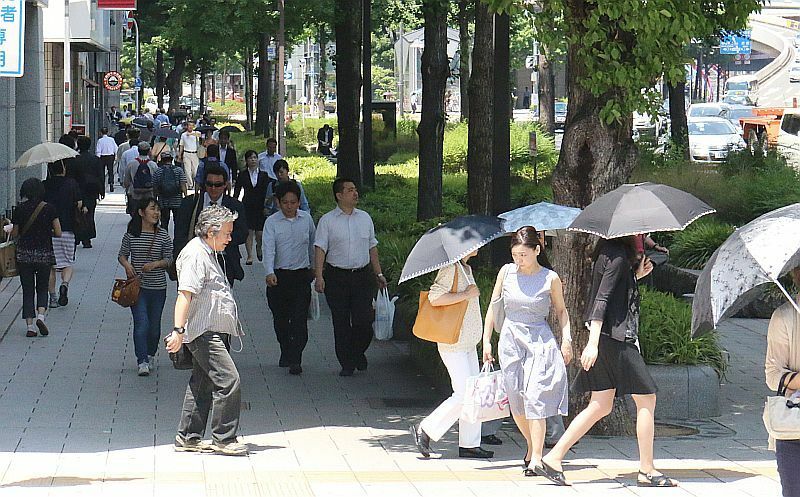 [写真]強い日差しに御堂筋ではビルや木の影に隠れるようにして歩く人が多く日傘の花もたくさん開いていた=27日午後1時ごろ、大阪市北区で