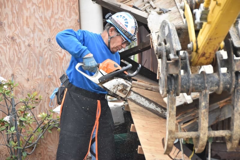 チェーンソーで納屋の板を切り取る藤野龍夫さん＝６月５日、石川県珠洲市