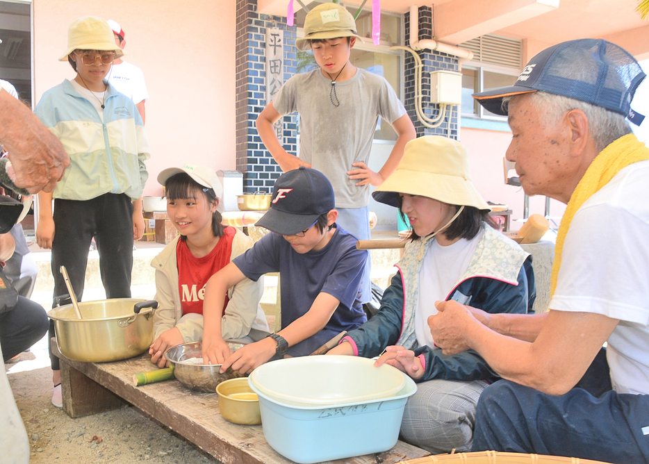 平田集落で行われていた伝統行事「ハマムチ」を体験する京都府の修学旅行生たち＝9日、鹿児島県宇検村平田