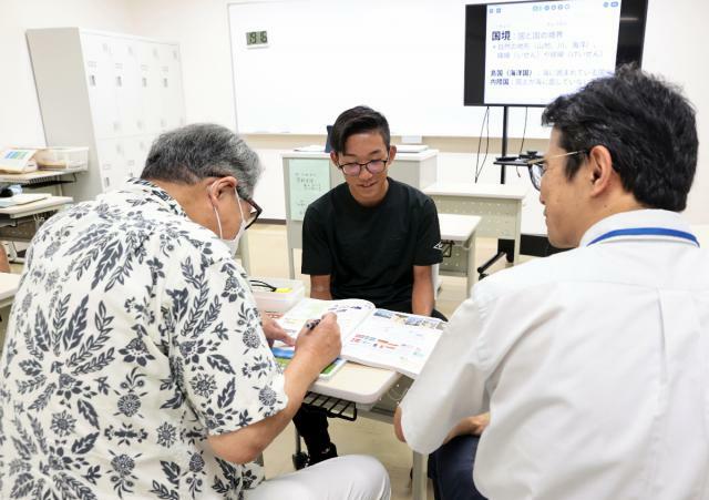 休み時間にクラスメートや教諭と談笑する原田曉耶さん（中央）＝宮崎市立ひなた中