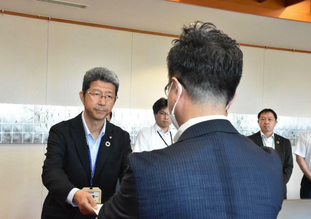 第三者委員会の設置を求める決議を読谷山洋司市長に手渡す早瀨賢一議長（左）＝８日午後、延岡市役所