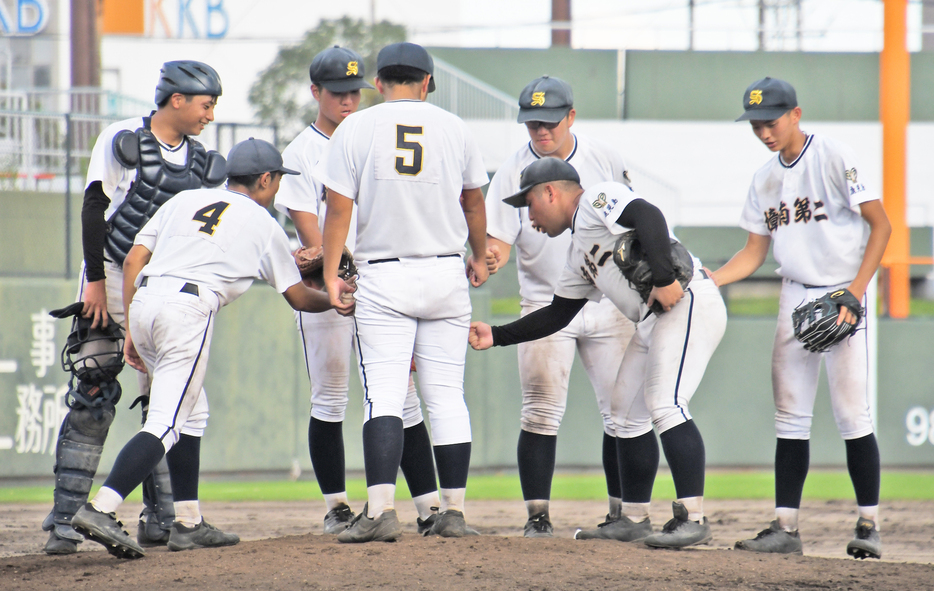 【2回戦・樟南第二―鹿児島実業】8回、走者を背負いピンチの場面にマウンドに仲間が集まり声を掛け合う＝16日、鹿児島市の平和リース球場