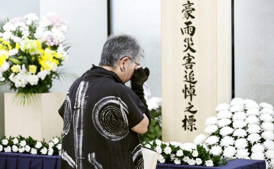 西日本豪雨から6年となり、岡山県倉敷市真備町地区で献花し目頭を押さえる地元住民。知人らを亡くした当時を思い出し「胸が痛くなり涙ぐんでしまった」と話した＝6日午前