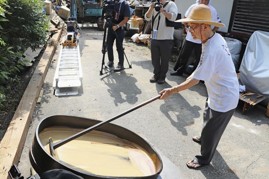 「天日黒目」の作業で漆の樹液をかき混ぜる大徹八井漆器工房の八井汎親会長＝23日午前、石川県輪島市