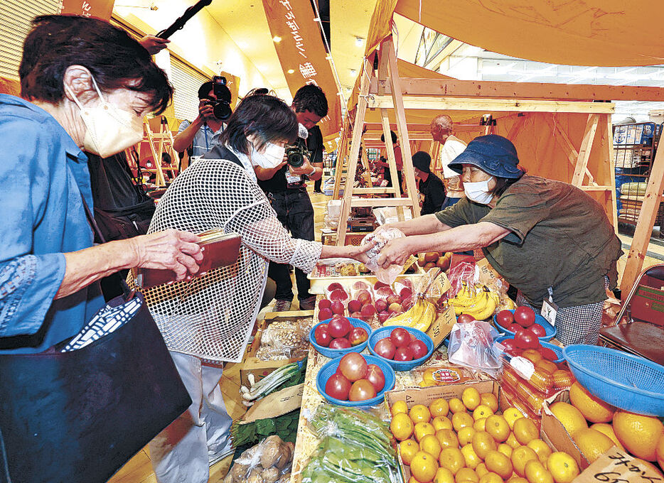 輪島市宅田町の商業施設で出張開催された輪島朝市で、野菜や果物を買い求める客＝１０日午前