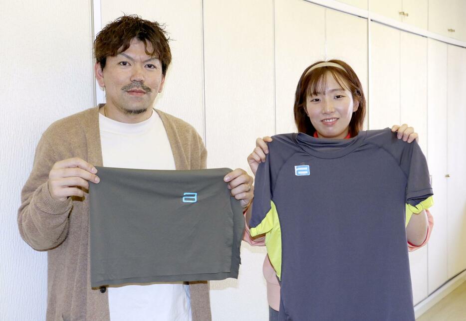 アタゴが製造した特製のウエアを手にする三田村知紀さん（左）と田中芹那さん＝3月、福井市