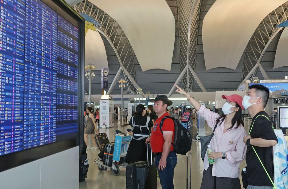 関西空港の国際線出発ロビーで便を確認する人たち＝20日正午ごろ