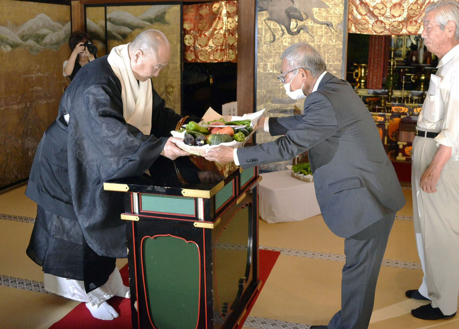 高野山の金剛峯寺で行われた夏野菜の奉納式で、「高野山麓精進野菜」を受け取る今川泰伸宗務総長（左）＝9日午後、和歌山県高野町