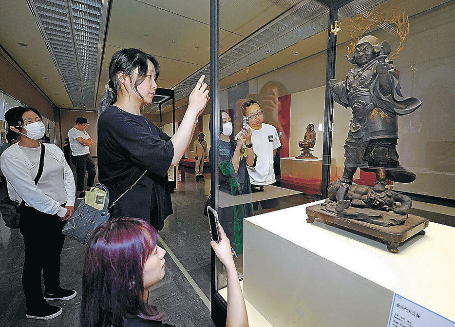 「毘沙門天立像」にカメラを向ける来場者=金沢市の石川県立美術館