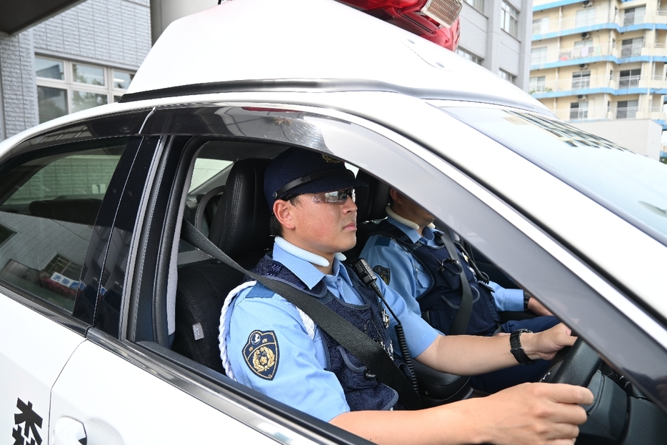 本格運用を前にサングラスを着用し、警察車両に乗る警察職員＝6月21日、青森市