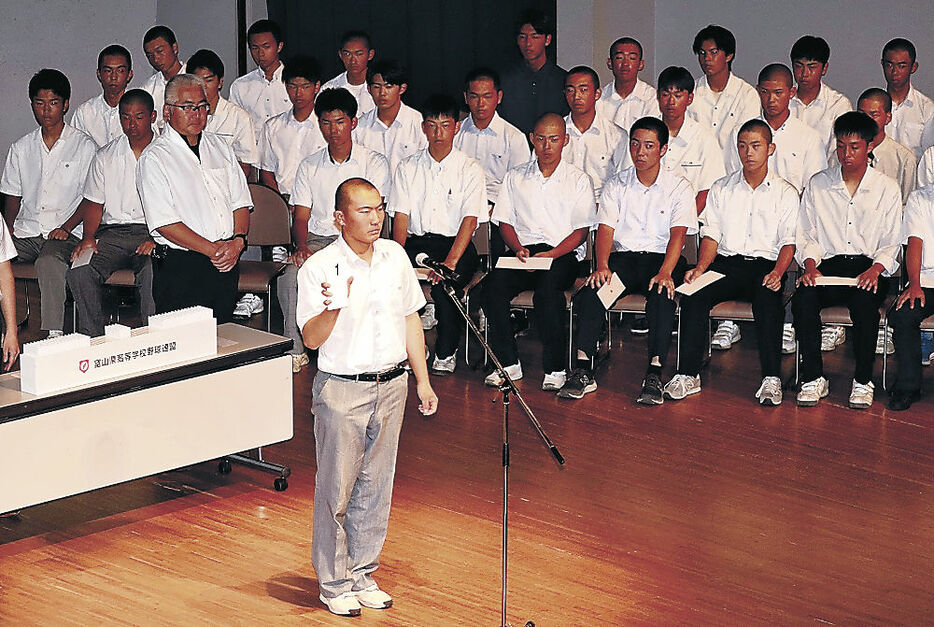 くじの番号を発表する富山商の鶴田主将（手前）＝射水市のアイザック小杉文化ホールラポール