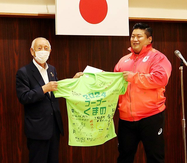 山本会長（左）から、応援メッセージ入りの記念Ｔシャツを受け取る村上選手