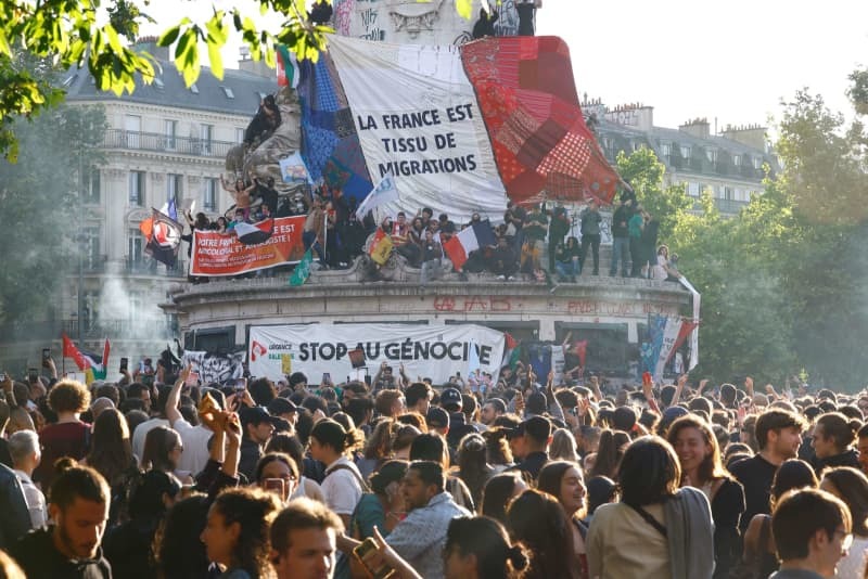 下院総選挙の決選投票後、パリのレピュブリック広場に集まった人々。「フランスは移民の国だ」と書かれた手作りの国旗を掲げた＝７日（共同）