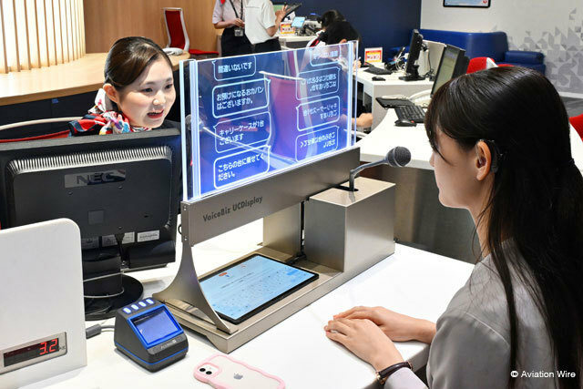 羽田空港で実施されたVoiceBiz UCDisplayの実証実験で聴覚障がいを持つ利用者役の社員（右）と字幕でやり取りするJALのグランドスタッフ＝24年7月2日 PHOTO: Tadayuki YOSHIKAWA/Aviation Wire