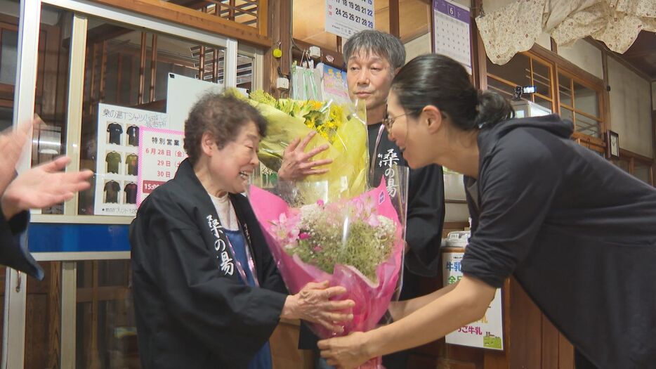 客から花束を受け取る母・節代さん