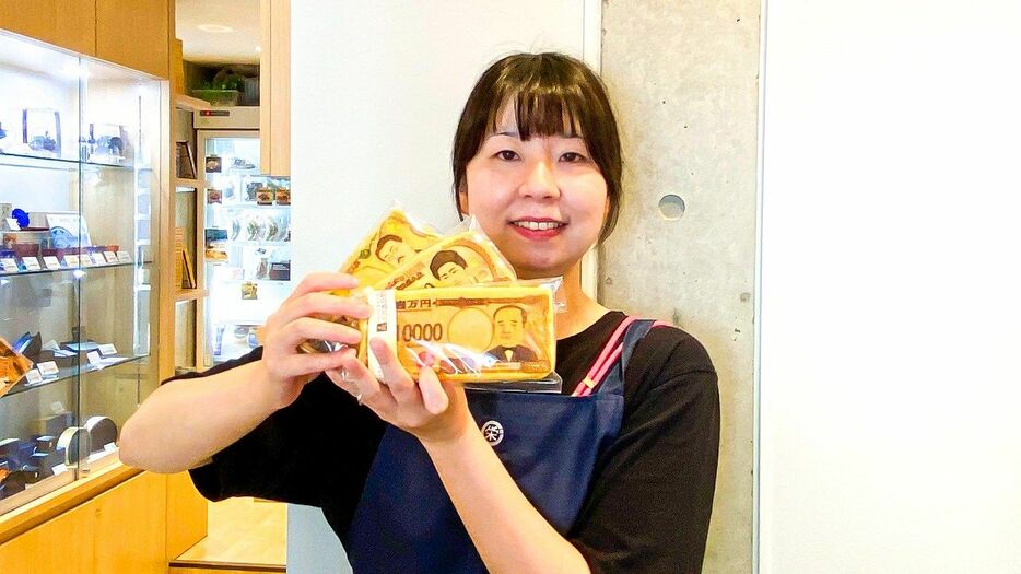 「お札パン」を手にする渋沢逸品館のスタッフ