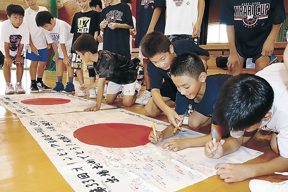 八村、馬場両選手に向けた応援メッセージを寄せ書きする児童＝富山市奥田北小