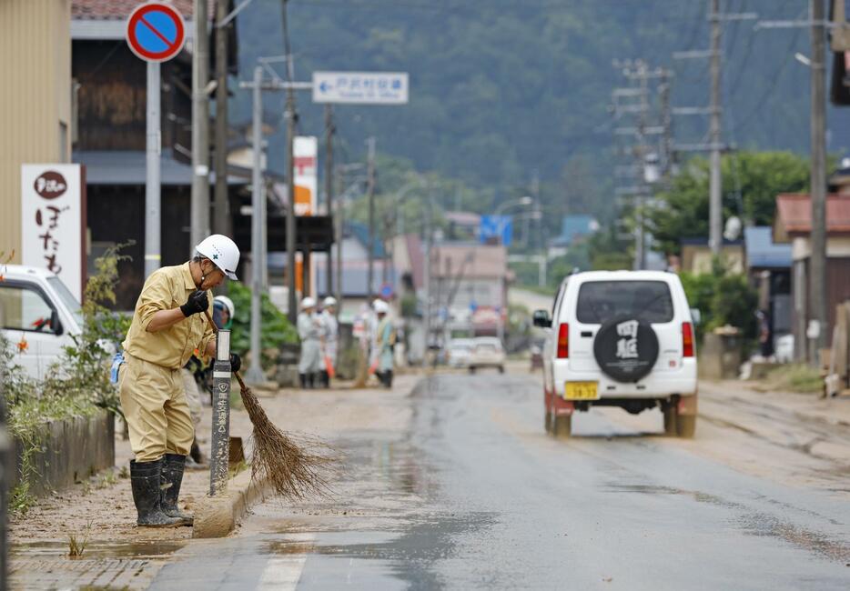 浸水した山形県戸沢村の古口地区で国道47号を掃除する人＝27日午前9時25分