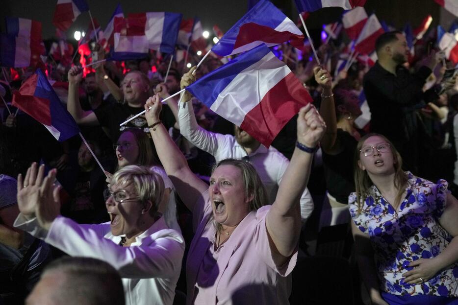 フランス国民議会総選挙の第1回投票で、国民連合（RN）の大躍進を伝える開票速報に沸き上がる支持者たち＝30日、エナンボーモン（AP＝共同）