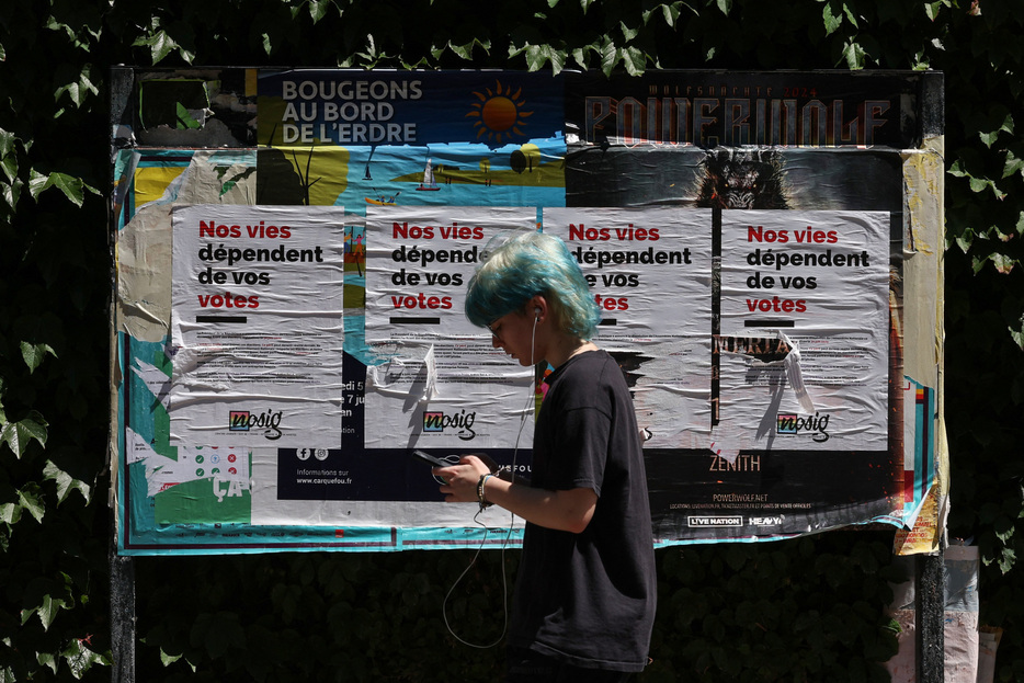 　７月２日、フランスで７日に行われる国民議会（下院）選挙の決選投票に向け、第１回投票で得票率トップとなった極右「国民連合（ＲＮ）」の過半数議席獲得を阻止しようと、有力政党の間で候補者を調整する動きが加速している。写真は６月、仏ナントの街頭に貼られた選挙関連のポスター前で撮影（２０２４年　ロイター/Violeta Santos Moura）
