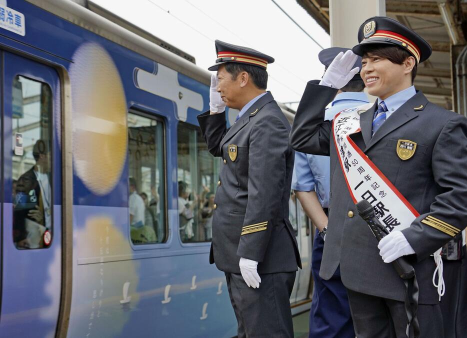 JR近江今津駅の一日駅長に就任し、記念列車を見送る西川貴教さん（右）＝20日午前、滋賀県高島市