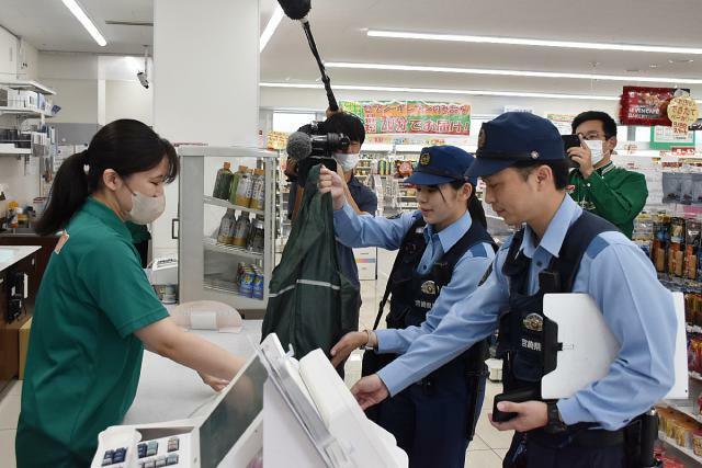 制服姿での買い物が解禁され、コンビニで食品を購入する県警の警察官＝１日午前、宮崎市