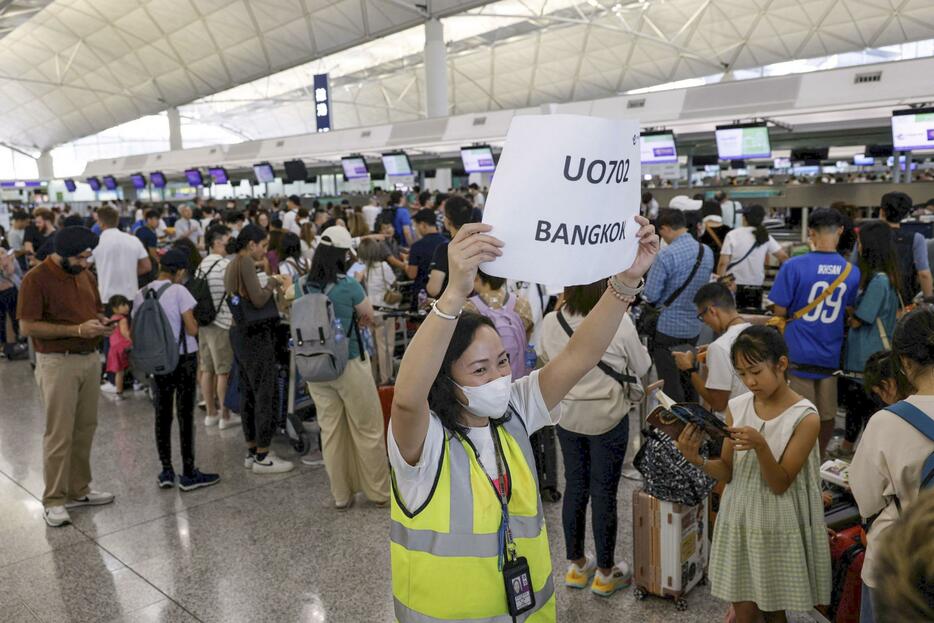 19日、システム障害が発生した香港の国際空港でカウンター前に並ぶ乗客（ロイター＝共同）