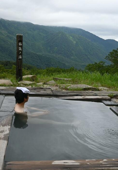 雄大な景色を眺めながら露天風呂を楽しむ観光客=7月21日、糸魚川市の蓮華温泉