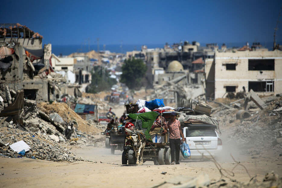 ３日、パレスチナ自治区ガザ南部のハンユニスで、イスラエル軍の攻撃で破壊された建物を通り過ぎる人。